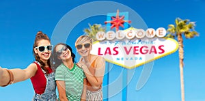 Female friends taking selfie over las vegas sign