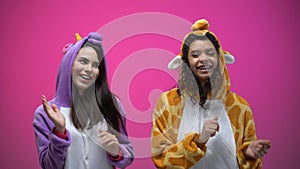 Female friends in unicorn and giraffe pajamas dancing, carnival party, fun time