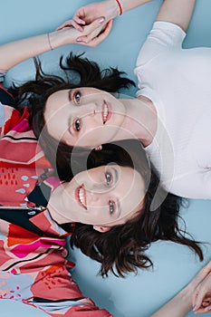 Female friendship of two twin sisters, lying on the floor