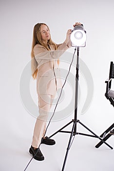 Female gaffer works with constant light in studio
