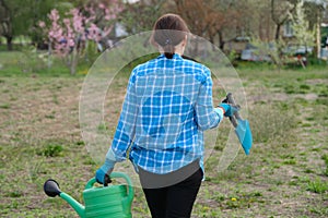Female gardener holding watering can and garden tools
