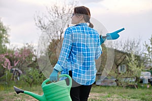 Female gardener holding watering can and garden tools
