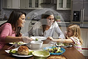 Female gay couple and daughter having dinner in their kitchen