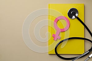 Female gender sign, stethoscope and notebook on beige background, top view with space for text. Women`s health concept