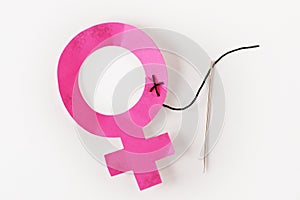 Female gender symbol sewn with neddle and thread - Concept of abuse and violence against women