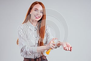 Female ginger redhead businesswoman in a striped shirt useing sunscreen suntan cream studio white background photo