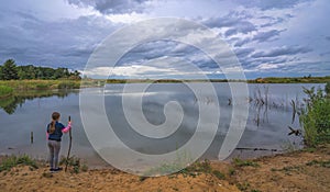 Female girl standing by a pond at sunset