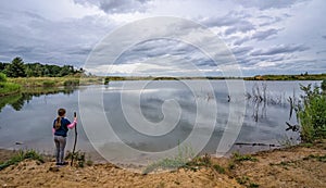 Female girl standing by a pond at sunset