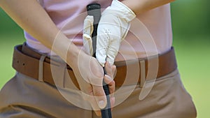 Female golf beginner player tightly holding club making shot practicing, closeup