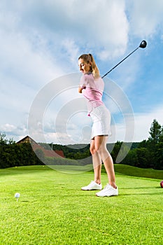 Female golf player on course doing golf swing