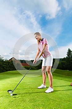Female golf player on course doing golf swing