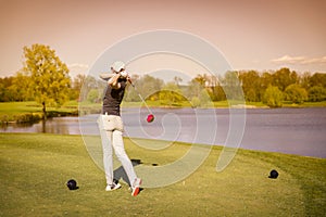 Female golf player teeing off.