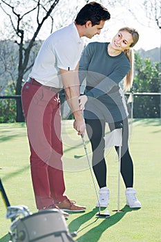 Female golf player training man