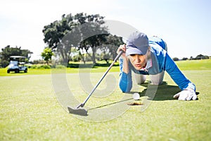 Female golfer blowing her ball on putting green