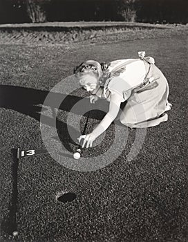 Female golfer crouching to line up a shot