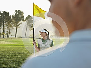 Female Golfer Holding Flag On Golf Course