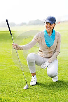 Female golfer kneeing on the putting green