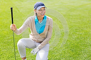 Female golfer kneeing on the putting green