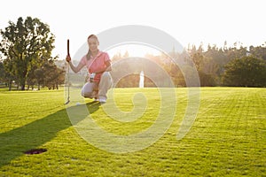 Female Golfer Lining Up Putt On Green