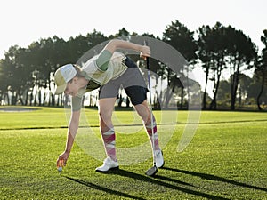 Female Golfer Placing Ball On Tee