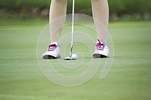 Female golfer putting on green.