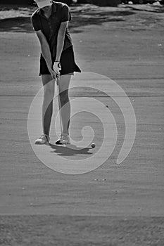 Female golfer putts in black and white photo