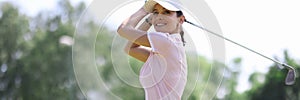 Female golfer smiles and looks along after making hit with club