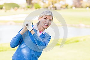 Female golfer standing holding her club smiling