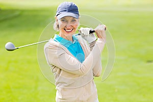 Female golfer taking a shot and smiling at camera