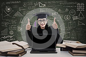 Female graduate giving thumbs up with copy space