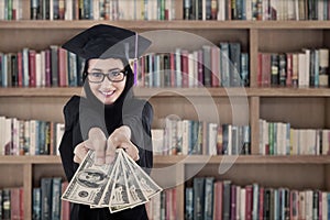 Female graduate holding money at library