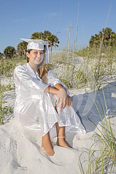 Female Graduate Sitting On A Sand Dune