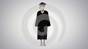 Female graduate student in a medical mask standing on gradient background.