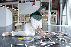 Female graphic designer in hijab checking photographs in office