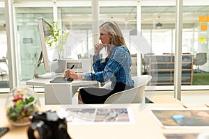 Female graphic designer using graphic tablet at desk