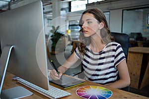 Female graphic designer using graphics tablet at desk