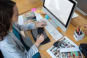 Female graphic designer using graphics tablet at desk