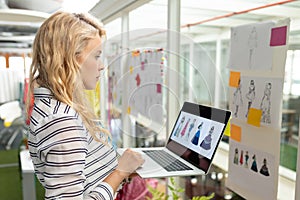 Female graphic designer using laptop in design studio