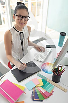 Female graphic designer using graphic tablet at desk in a modern office