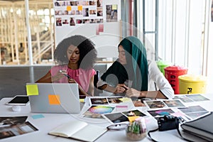 Female graphic designers discussing over laptop at desk