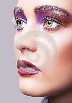 Female green pistachio colour eye with evening violet eyes shadows, white eyelashes and purple lips makeup