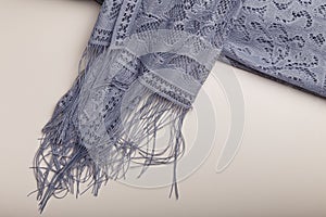 Female grey lace shawl with fringe and flowers ornaments on white table background. Clothing and accessories.