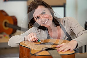 female guitar maker builds string tensioner on new guitar photo