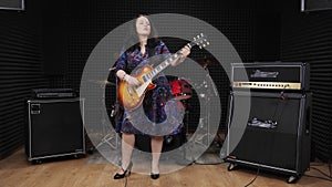 Female guitar player is performing country song on electric guitar at professional sound recording studio. Woman plays guitar at r