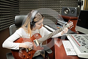 Female guitarist composing music in studio