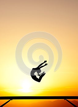 Female gymnast on balance beam in sunset