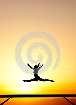 Female gymnast on balance beam in sunset