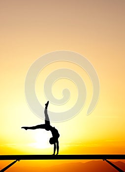 Female gymnast on balance beam in sunset