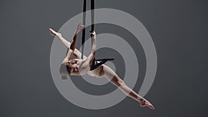 Female gymnast isolated monochrome studio background. Close up shot girl aerial dancer on acrobatic trapeze with straps