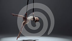 Female gymnast isolated monochrome studio background. Close up shot girl aerial dancer flying on acrobatic trapeze with